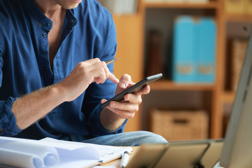 homem-irreconhecivel-vestido-casualmente-usando-o-smartphone-no-trabalho-no-escritorio_orig